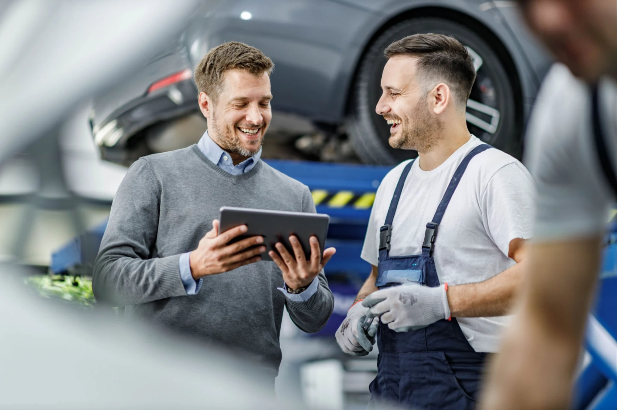 Kundenberatung in der Werkstatt: Mechaniker erklärt einem Kunden den Befund am Fahrzeug